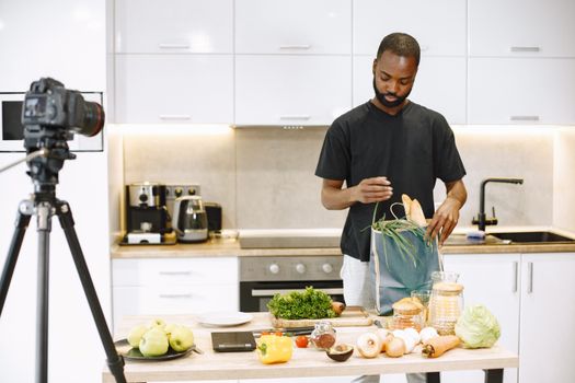 A man sets up ingredients for a cooking video blog in his modern kitchen.