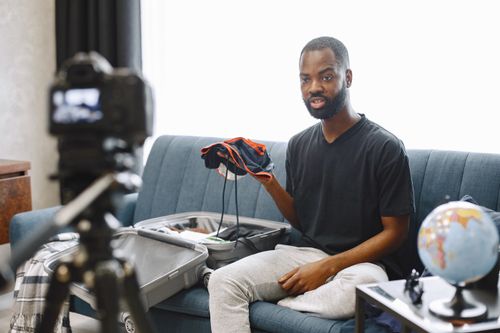 Free A vlogger records a travel vlog while unpacking a suitcase indoors with camera setup. Stock Photo