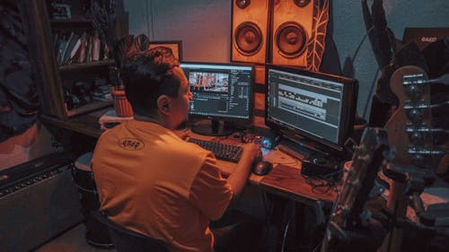 Man sitting in front of Two Monitors