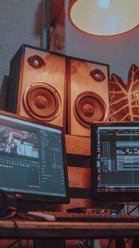 Contemporary video editing setup with dual monitors and speakers in a recording studio.