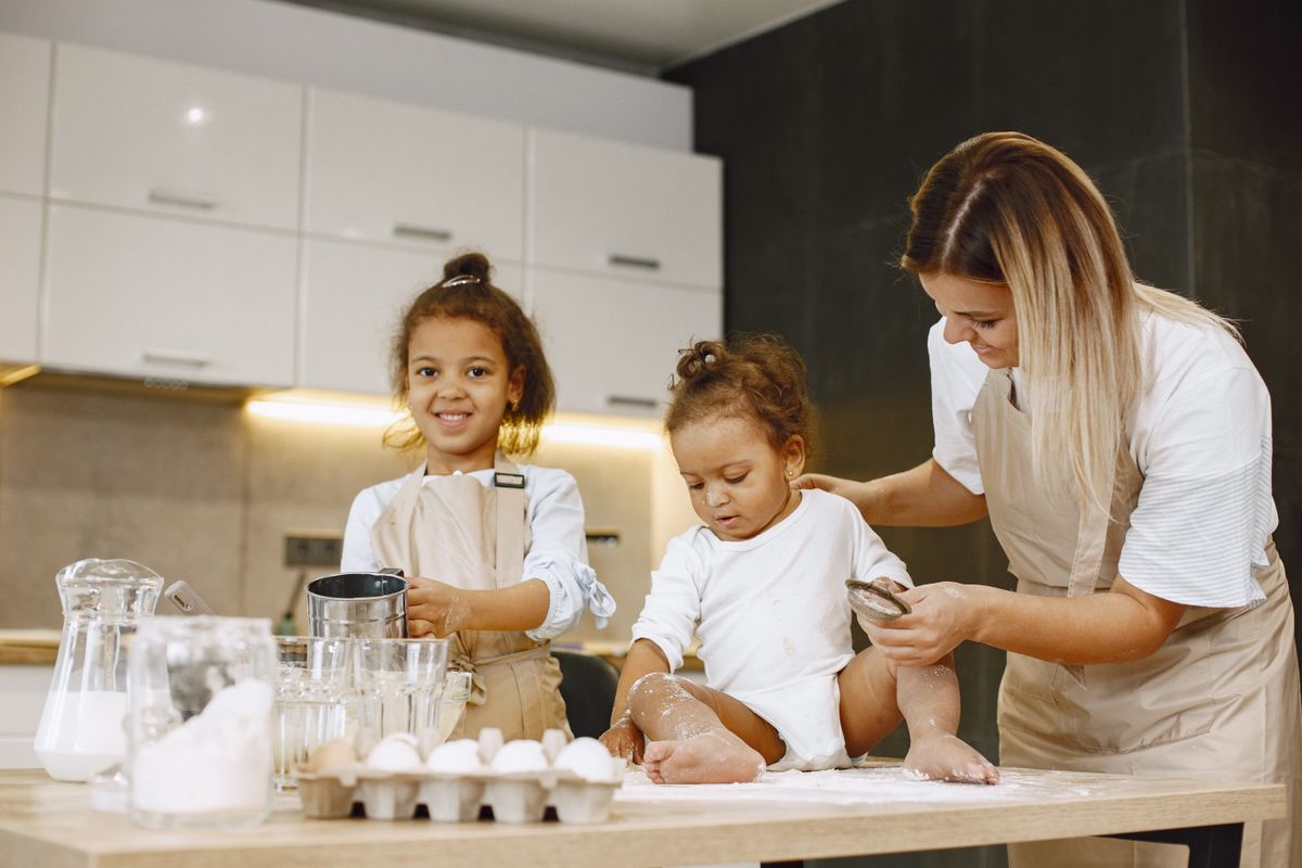 Madre e hijos preparando comida juntos en una cocina luminosa