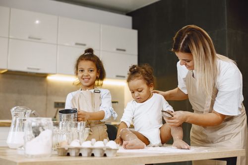Free A mother and her children enjoying a fun baking session in the kitchen. Stock Photo