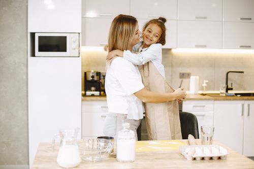 Free A heartwarming moment of mother and daughter bonding while baking in the kitchen. Stock Photo