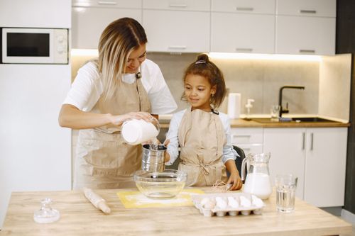 Free Mother and daughter enjoy baking in a modern kitchen, bonding over shared cooking activities. Stock Photo