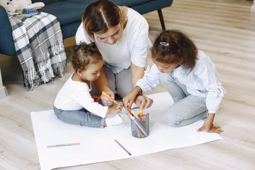 Free A mother and her children engage in a fun and creative coloring activity on the floor. Stock Photo