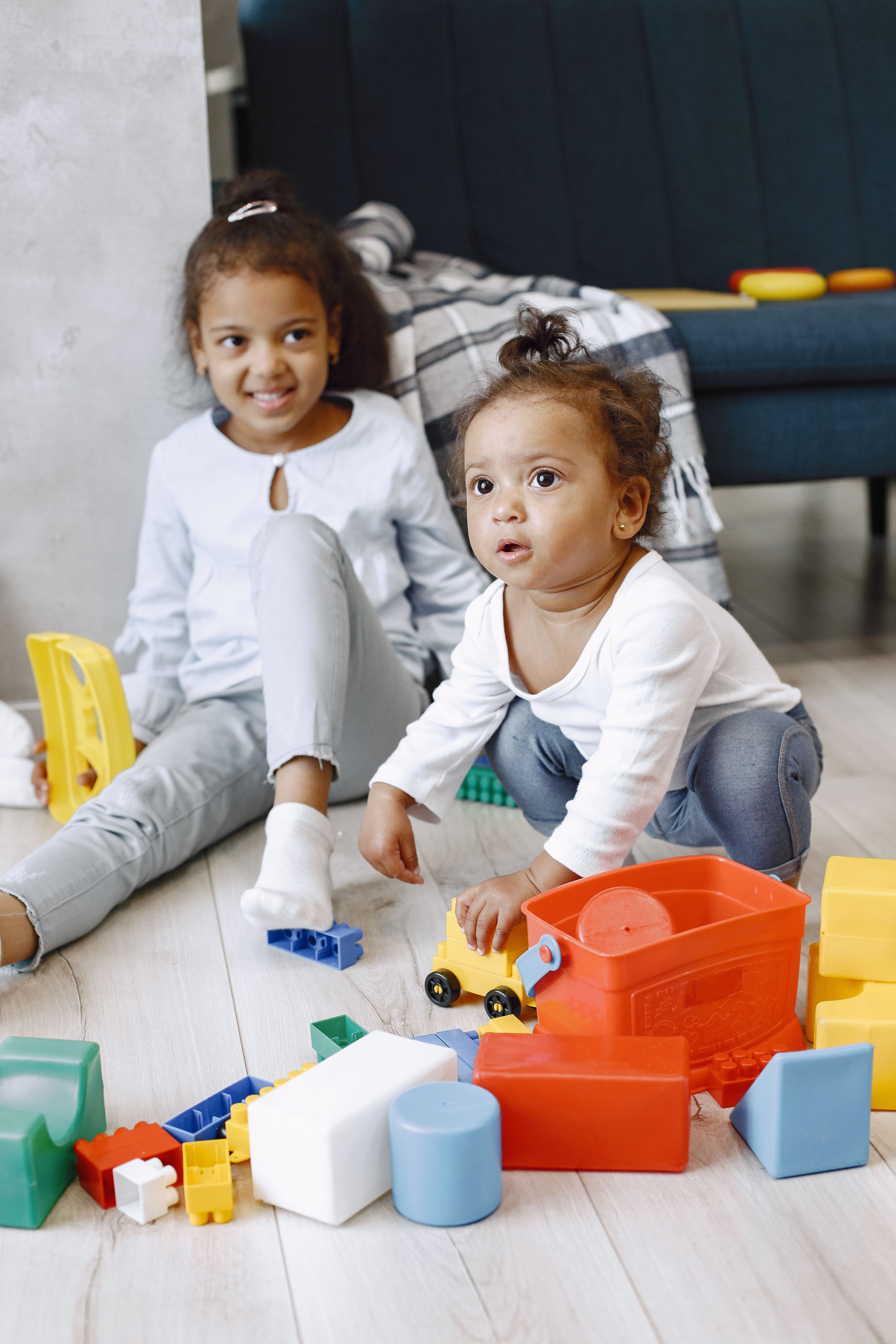 Two children playing happily together with colorful building blocks on the floor.