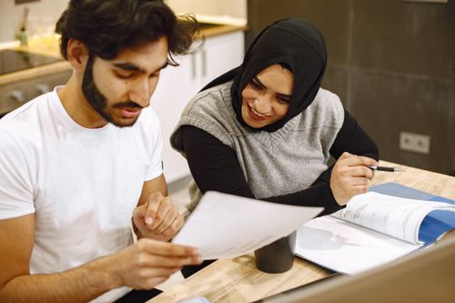 Free Middle Eastern couple smiling and studying together at home. Engaging in educational activities with documents. Stock Photo