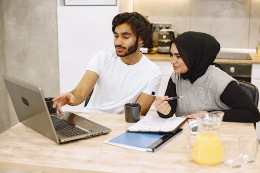 A man and woman, engaging in a collaborative work session with a laptop and notes on the table.