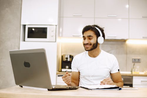Free Smiling Man in Headphones Talking on Call on Laptop Stock Photo