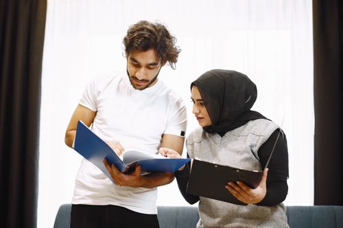 Free Two adults reviewing documents indoors, fostering teamwork. Stock Photo