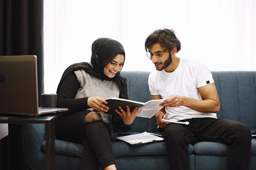 Free Two People Reading Documents on a Sofa Stock Photo