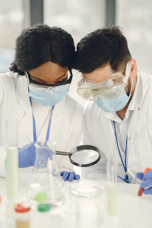 Man and Woman Looking at the Petri Dish Through Magnifying Glass