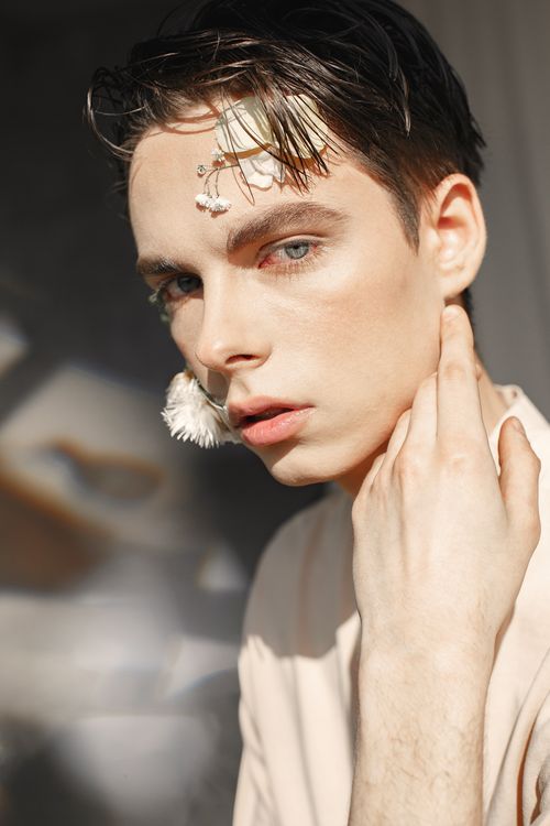 Free Striking portrait of a young man with floral accents highlighting artistic fashion style. Stock Photo