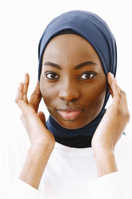 Elegant studio portrait of a woman wearing a blue hijab and white shirt, showcasing a serene expression.