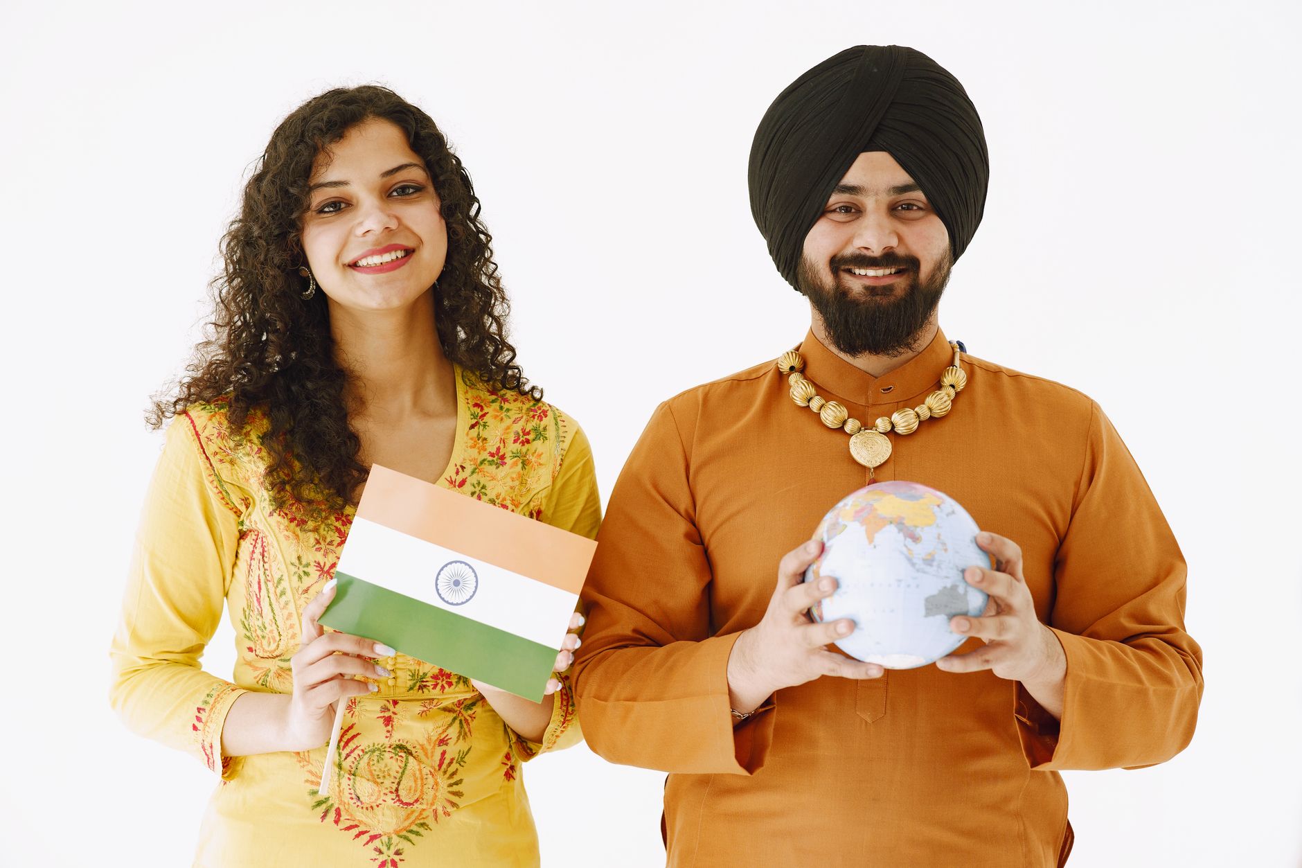 Happy Indian couple in traditional attire holding a flag and globe against a white background.