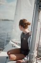 A Woman in Black Vest and Sitting on a Yacht