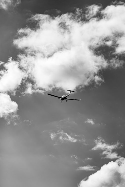 Free Artistic black and white photo of an airplane flying through a cloudy sky, showcasing the freedom of flight. Stock Photo