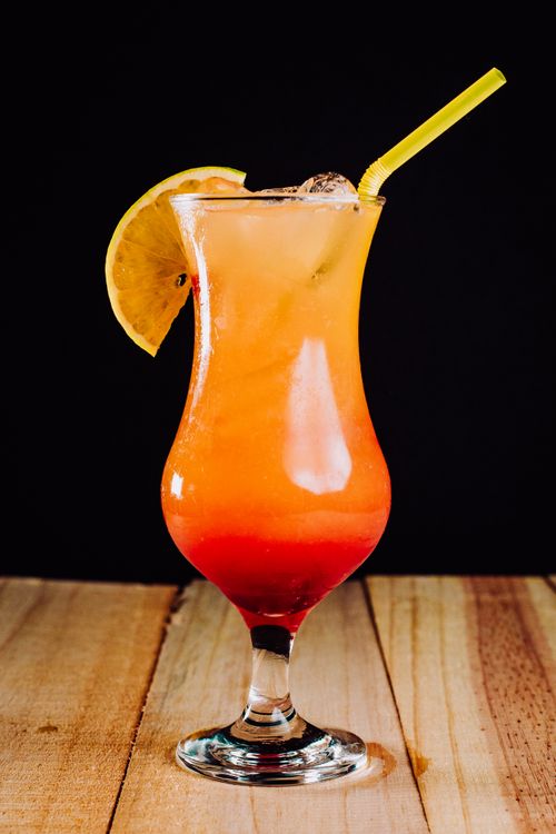 Free Colorful orange cocktail with lemon slice and straw on a wooden table, perfect for summer vibes. Stock Photo