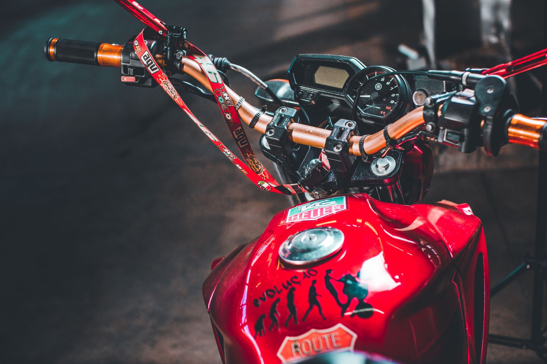 Close-up of a red motorcycle's handlebar with stickers and dashboard view.