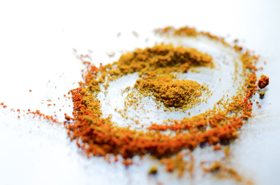Pó de cúrcuma amarelo-alaranjado em colher de madeira sobre superfície escura — tempero açafrão-da-terra
