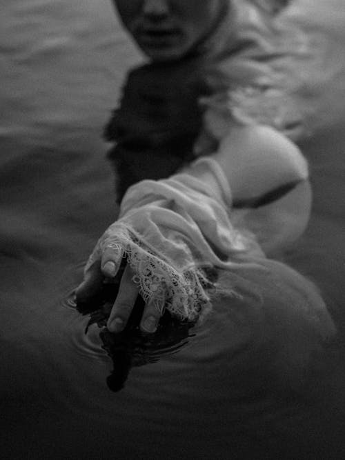 Grayscale Photo of a Person's Hand in Water