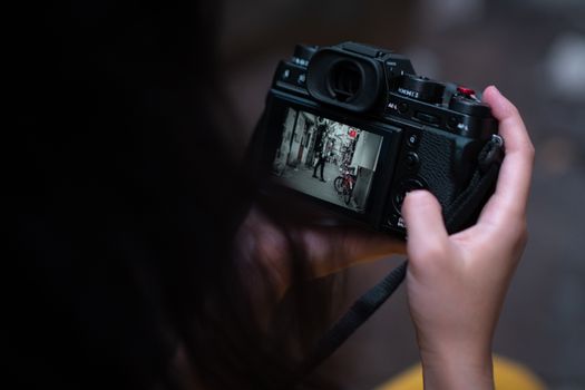 Close-up of hands holding camera displaying a street scene in focus.