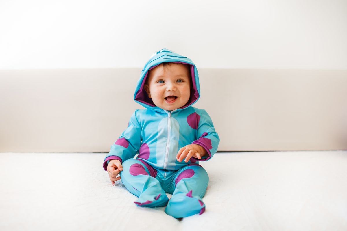 Smiling baby in a blue hooded monster onesie