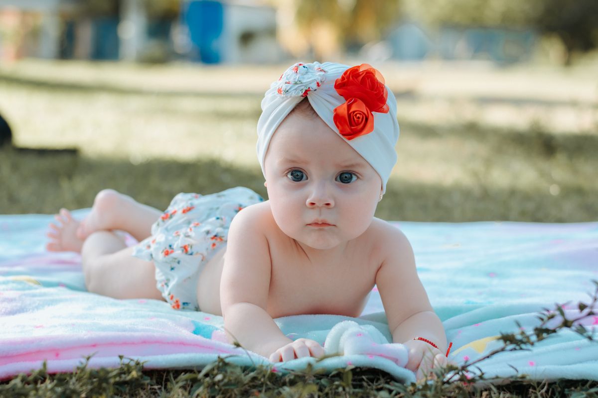 Baby lying on their tummy on a floor mat while awake, lifting their head toward the camera