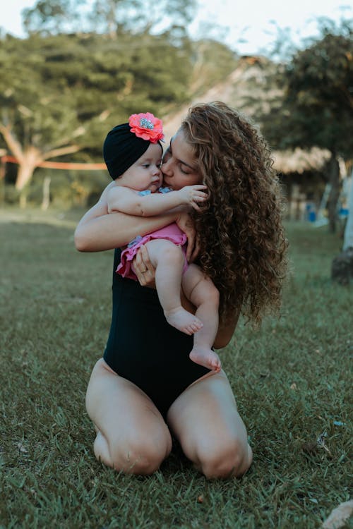 Woman in Black Swimsuit Holding a Baby
