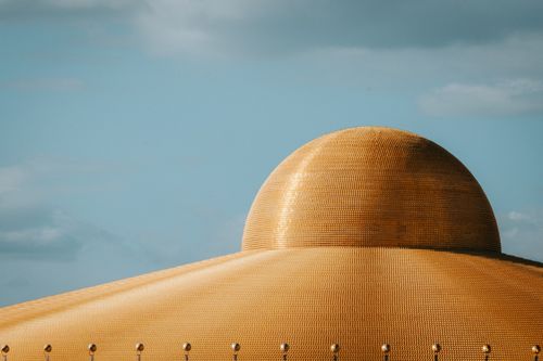 Free A stunning view of the golden dome at Wat Phra Dhammakaya temple under a blue sky. Stock Photo
