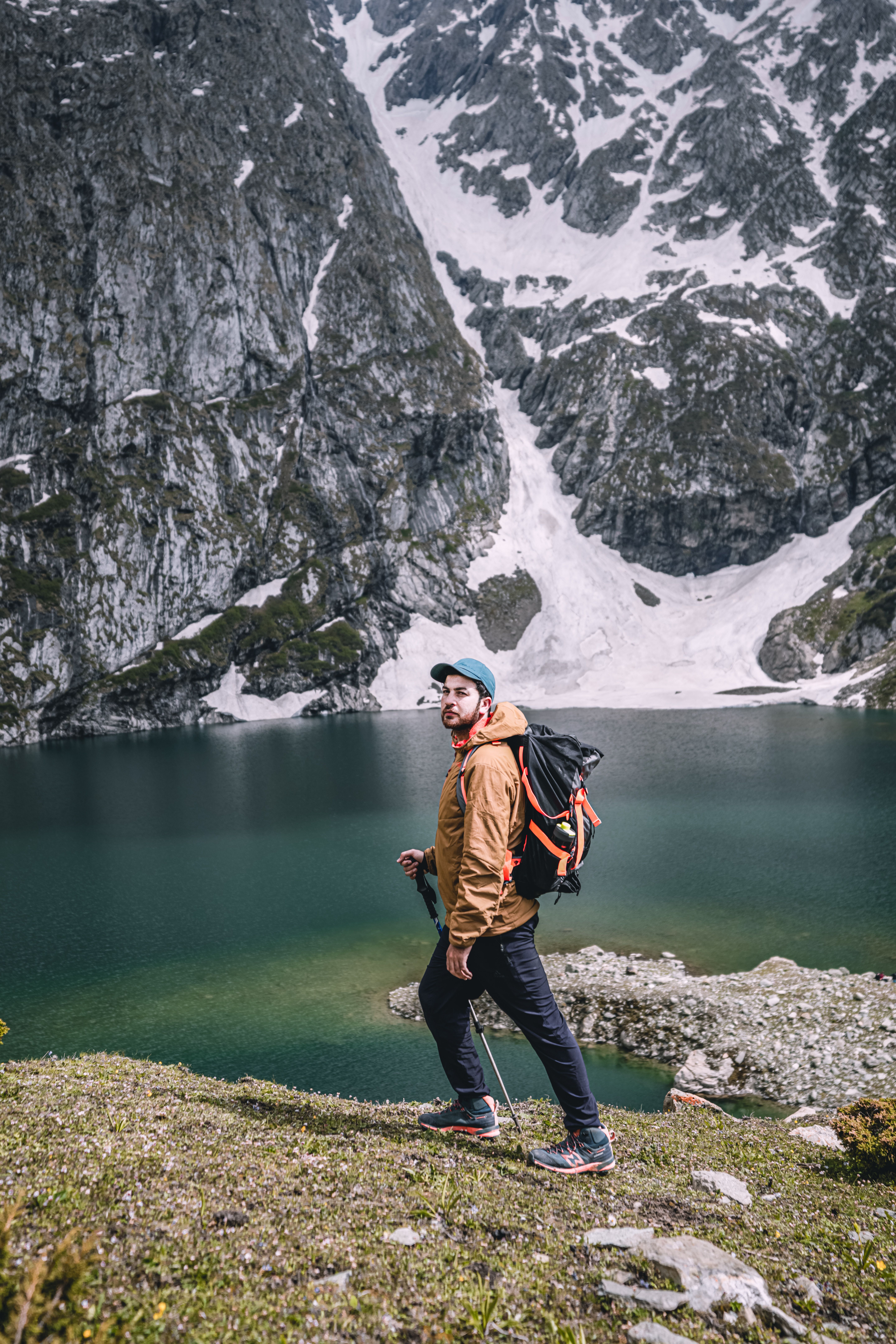 A Man Carrying His Backpack while Walking Near the Lake · Free Stock Photo