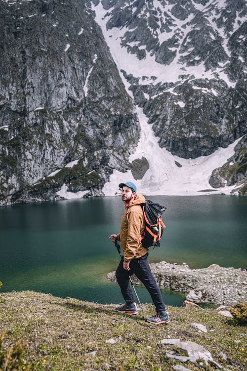 Free A Man Carrying His Backpack while Walking Near the Lake Stock Photo