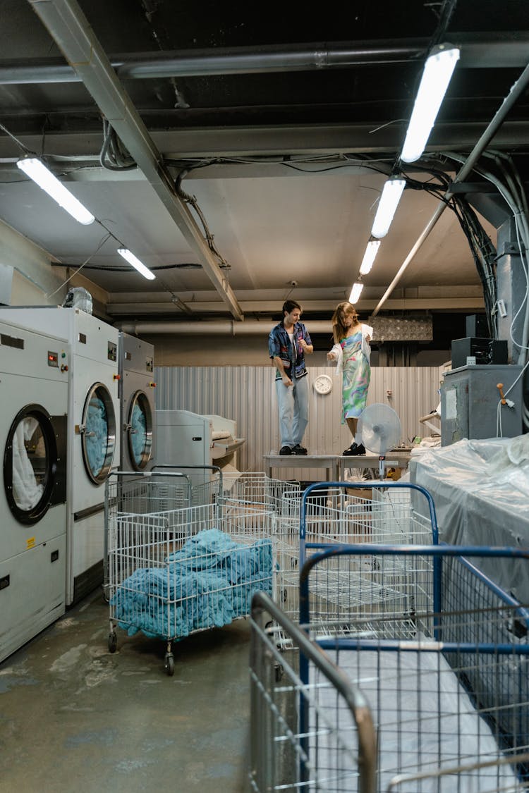 A Man And Woman Standing On The Table Inside The Laundry Facility