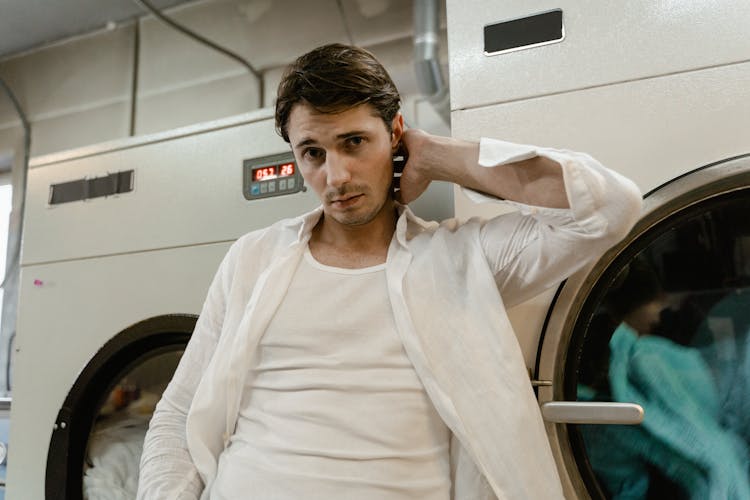 A Man Leaning On A Commercial Washing Machine