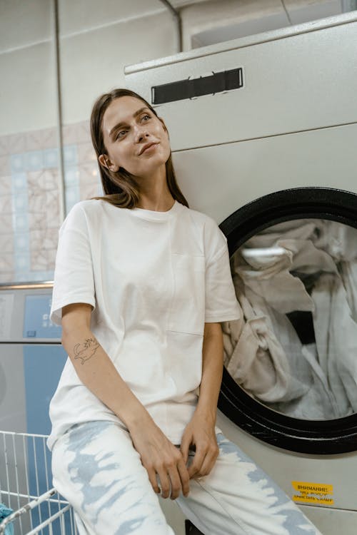 Free A Woman Sitting beside the Laundromat Stock Photo