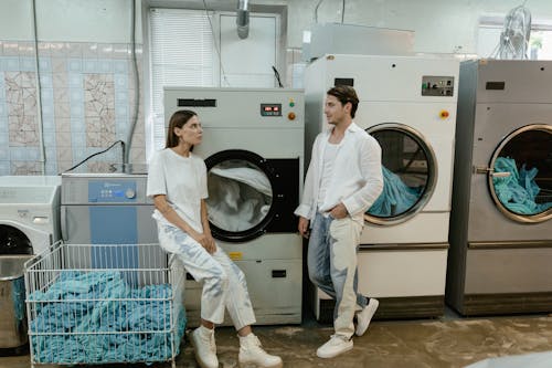 Free A Man and a Woman Beside Washing And Dryer Machines Stock Photo