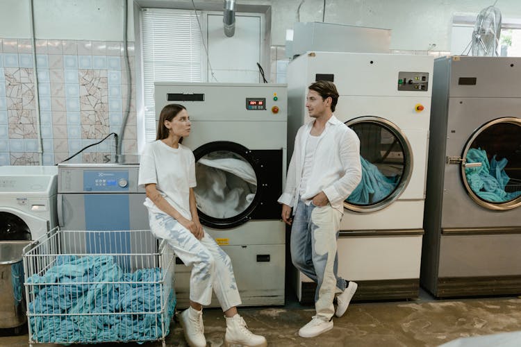 A Man And A Woman Beside Washing And Dryer Machines