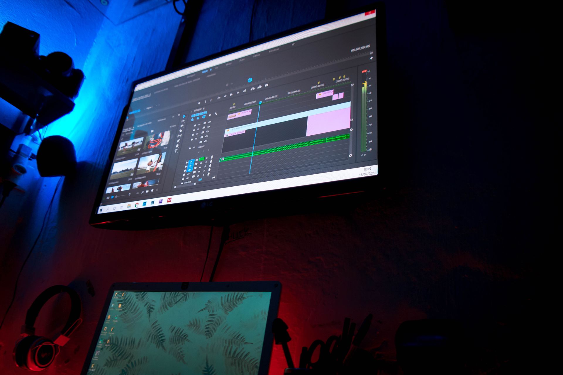 A dark room with computer screens displaying video editing software, creating a moody atmosphere.