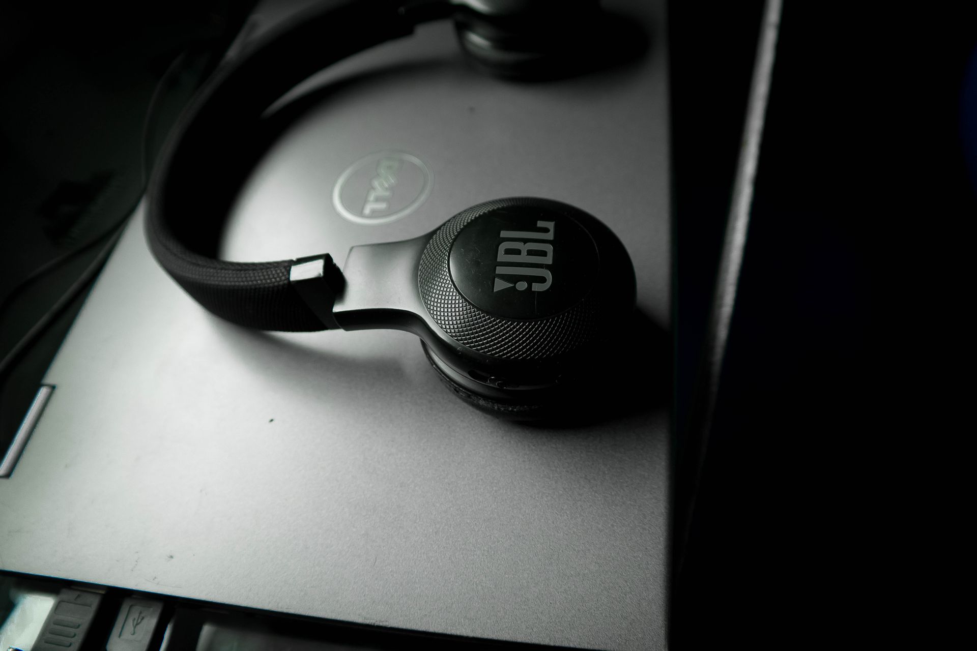 Black JBL wireless headphones resting on a closed Dell laptop, tech essentials for productivity.