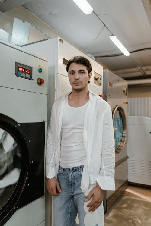 Free A Man Standing Beside Washing Machines Stock Photo