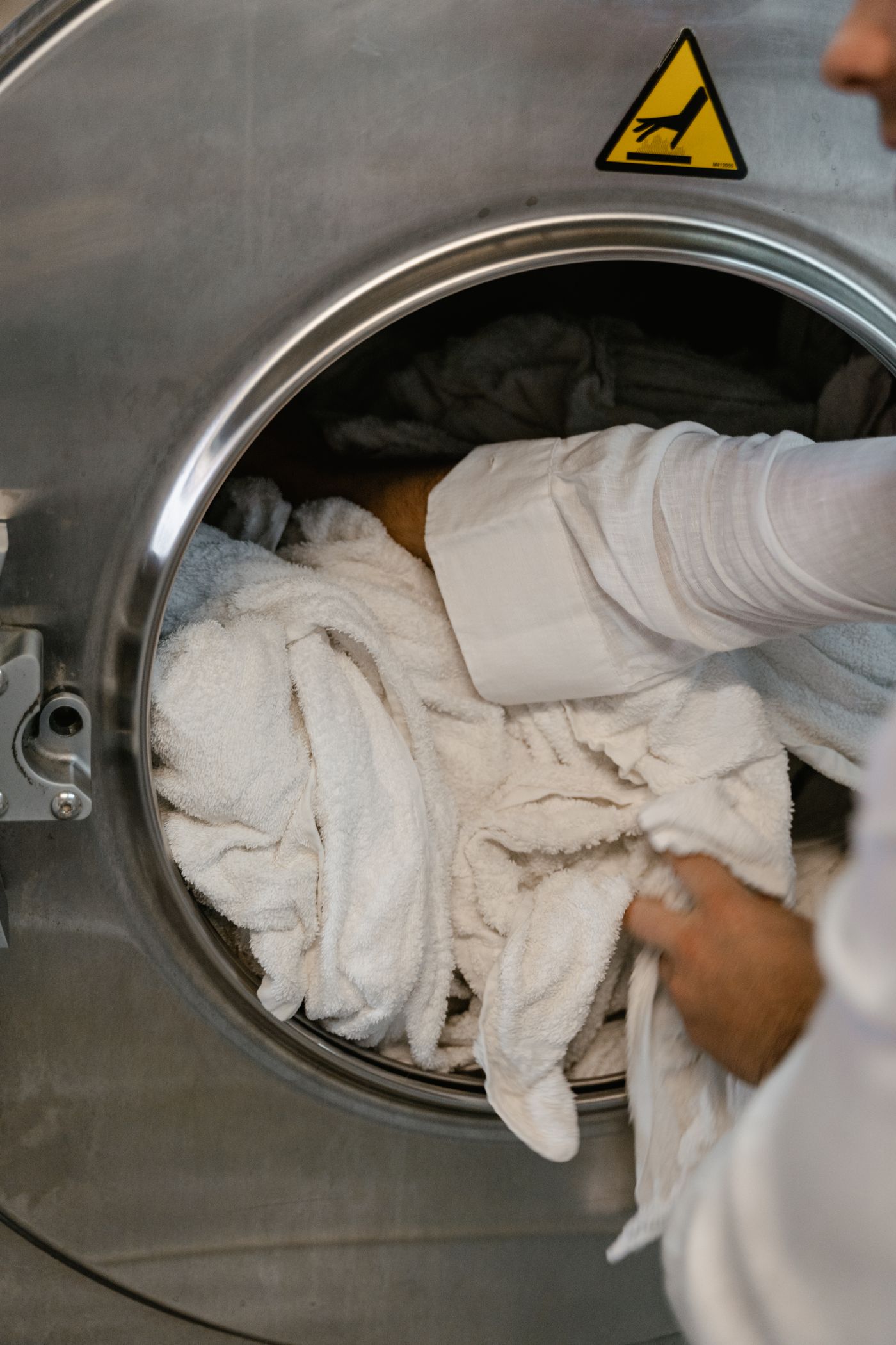 Professional laundry care with garments being loaded into a commercial washing machine