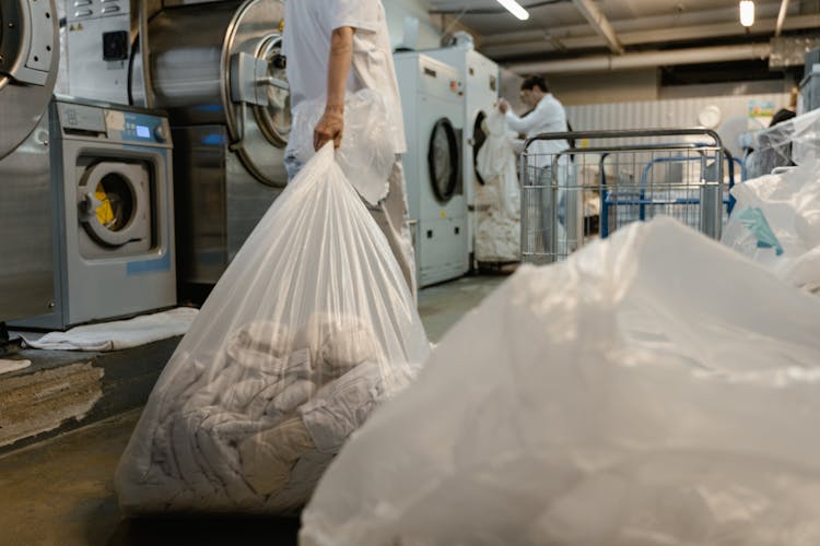 A Person Holding A Plastic Bag With Laundry 