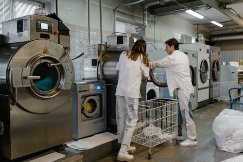 Free A Man and a Woman Washing Clothes using Washing Machine Stock Photo