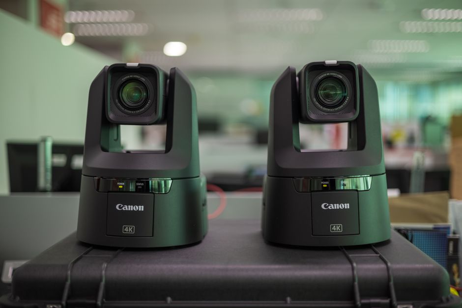 Two professional Canon 4K video cameras displayed on a protective case in an office setting.