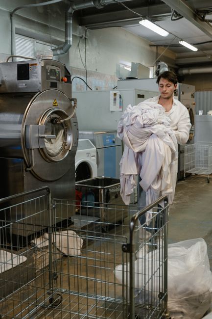 Person loading bedding into a washing machine