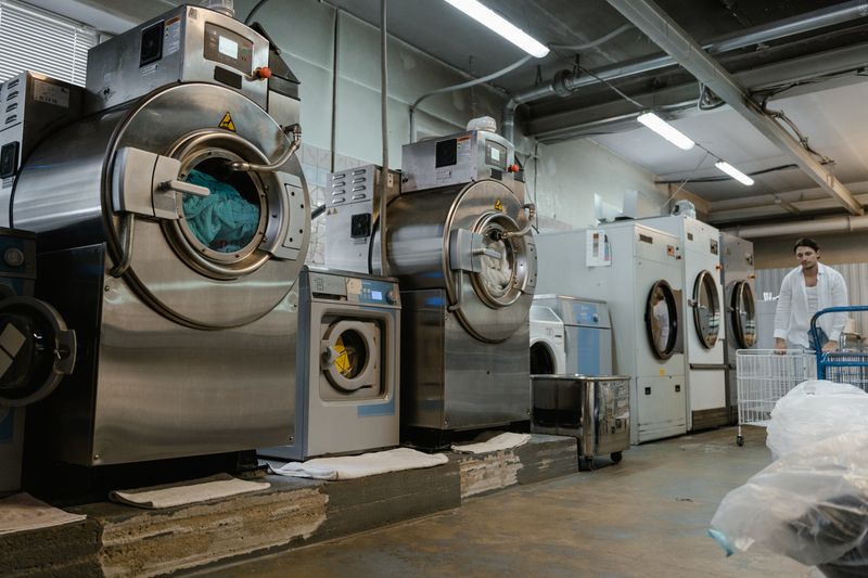 Foldly specialist pushing a cart of fresh laundry between washers
