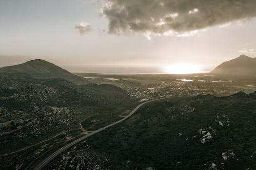 A breathtaking aerial view of mountains, valleys, and a winding road at sunrise, perfect for travel enthusiasts.