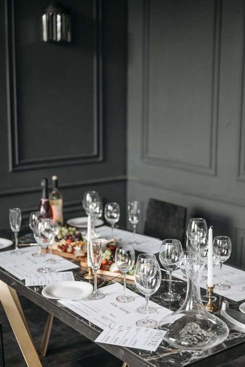 Free Elegant table setting with wine glasses and platters in a dark, stylish dining room. Stock Photo
