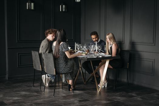 Group of adults enjoying a wine tasting session at a stylish restaurant setting.