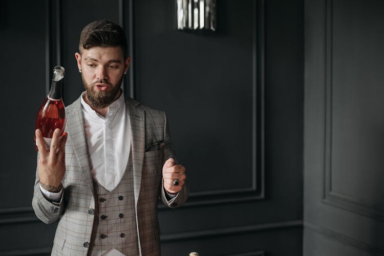 Young Bearded Man In Suit Holding Cognac Bottle